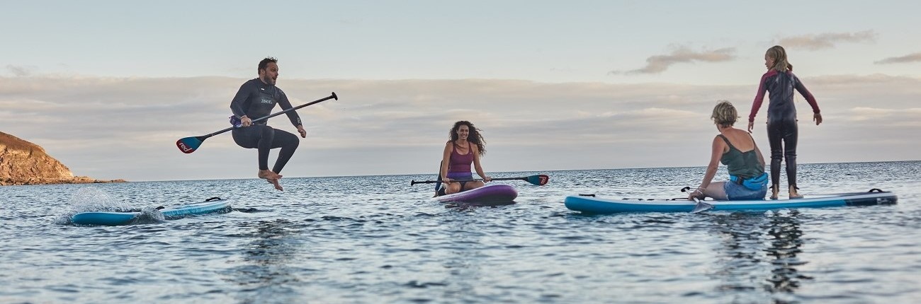Red-Paddle-Inflatable-SUP-group-of-friends-jumping-Stand-Up-Surf-Shop 1300x430